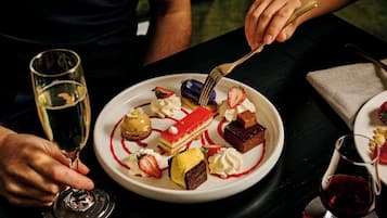 A dessert plate with various sweets and a glass of white wine.