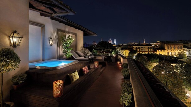 A rooftop terrace with a hot tub, lounge chairs, and ambient lighting.