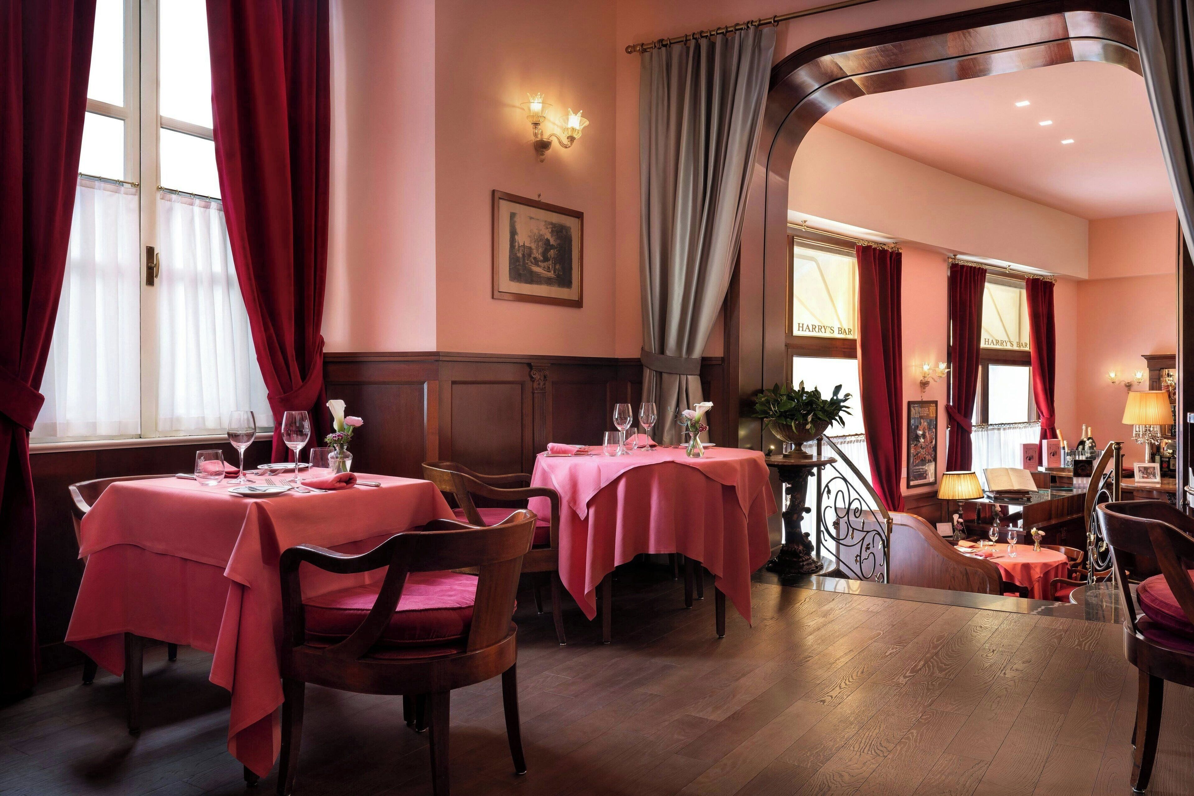 Ein Restaurant mit rosa Tischdecken, Holztischen und einer Treppe zu einer weiteren Ebene.