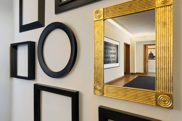 A hallway with various black and gold framed mirrors and a black circular object on the wall.