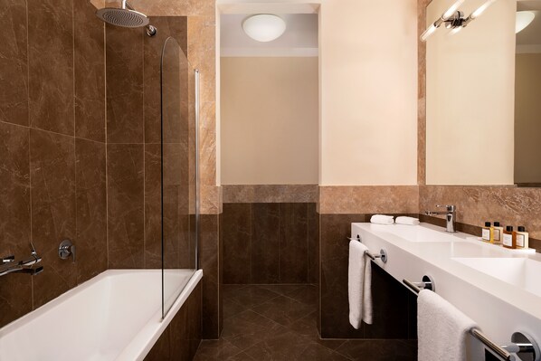 A modern bathroom with a bathtub, a shower, and a vanity with a sink and mirror.