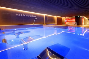 Uma piscina interior moderna com um letreiro 'METROPOLITAN', água cristalina e design elegante.