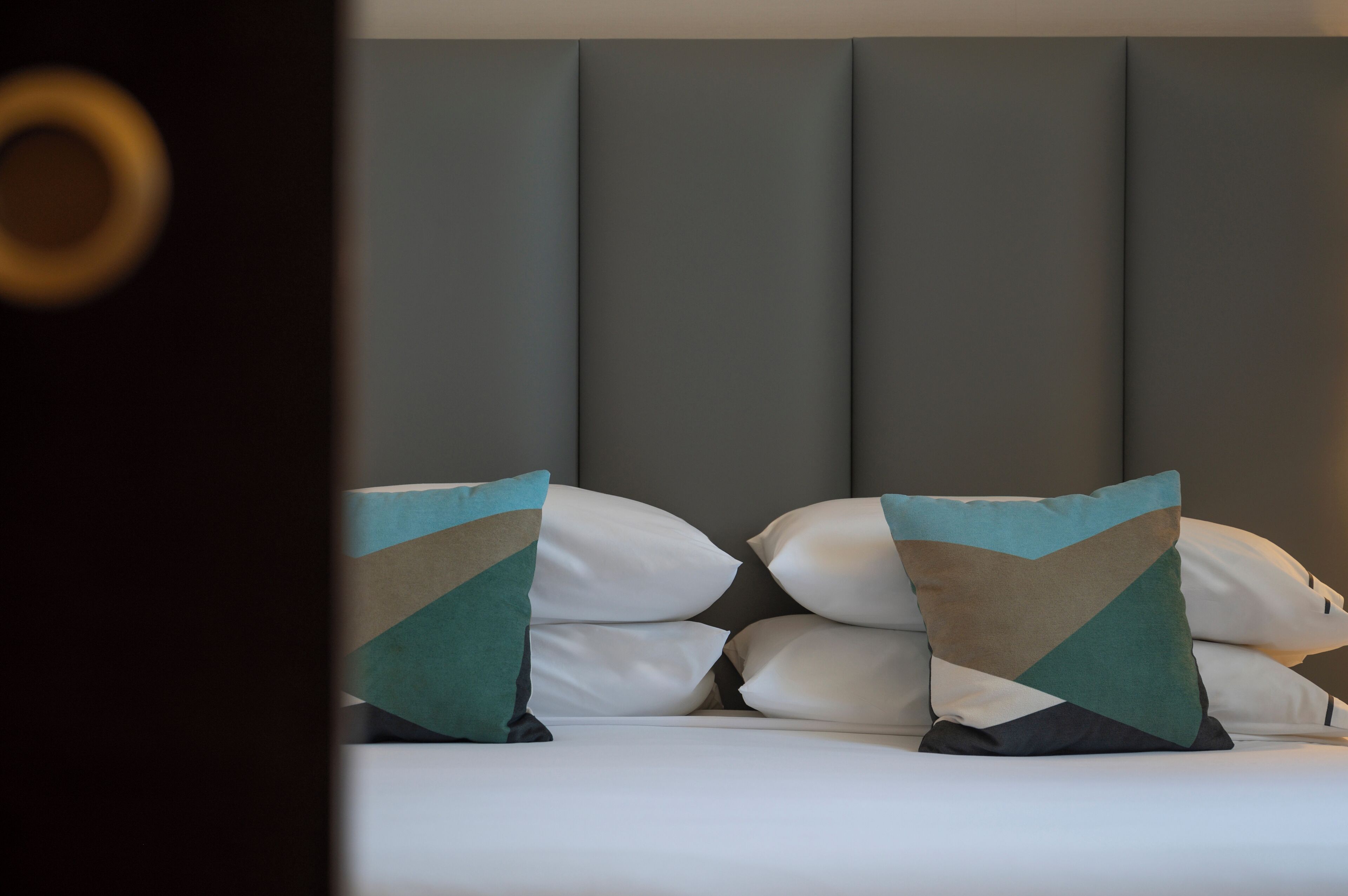Una cama con muchos almohadones y un cabecero.
