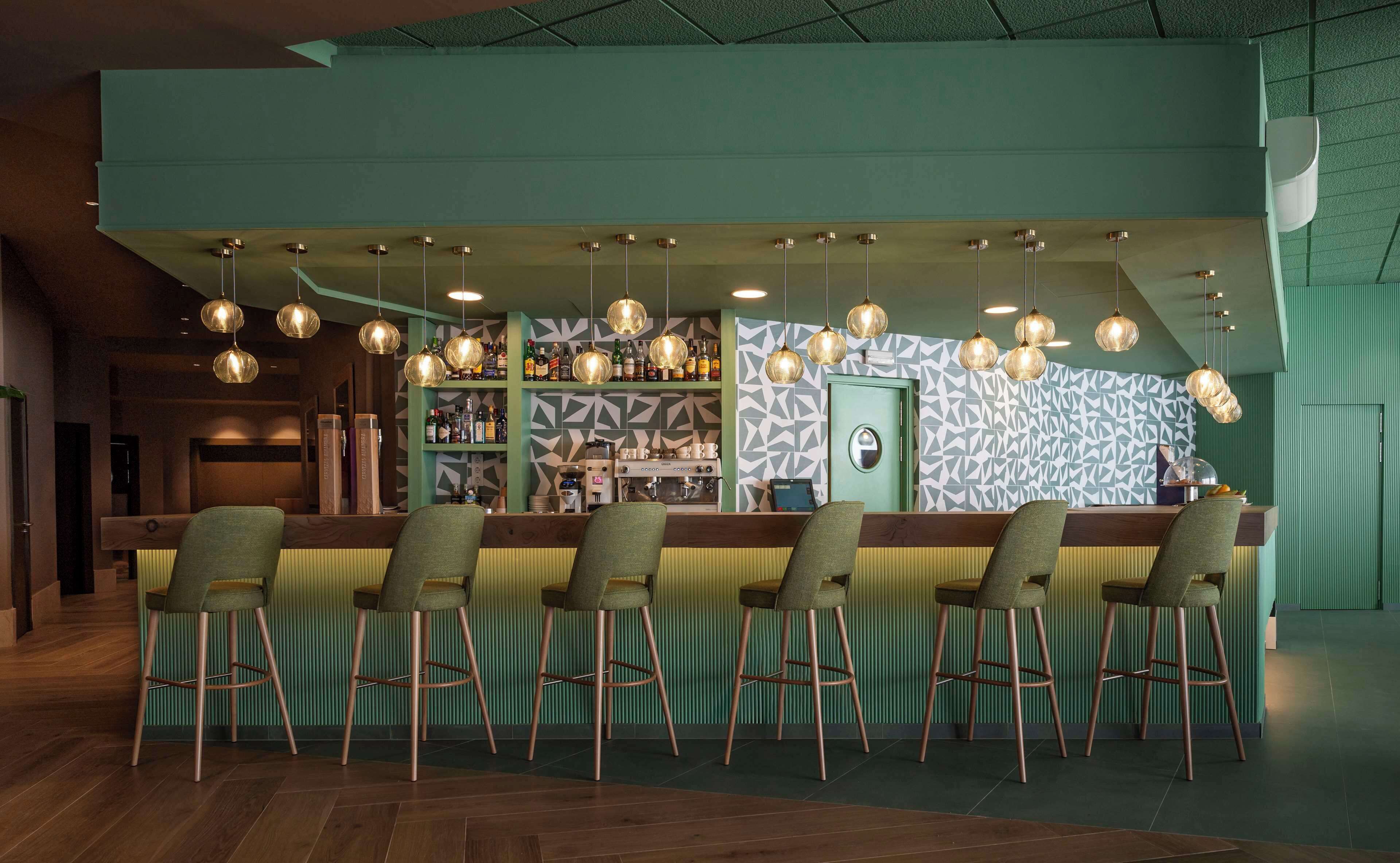A bar area with a counter, stools, and hanging lights.