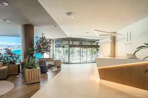 Un espace d’accueil moderne, avec un comptoir en bois, des sièges et de grandes fenêtres donnant sur la ville.