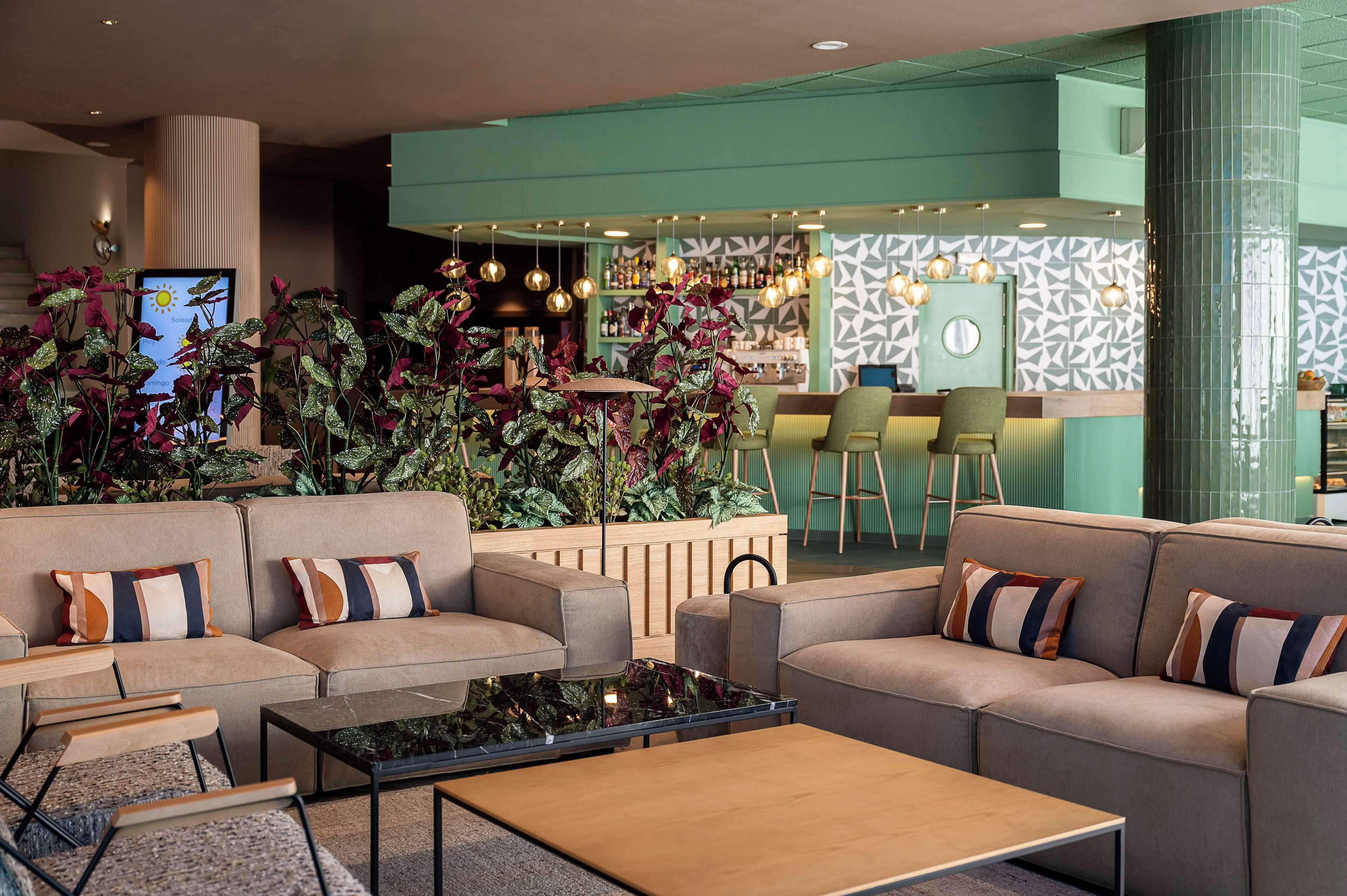 A modern lounge area with sofas, a coffee table, and a bar with stools.