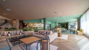 A spacious lobby with a central seating area, a staircase, and a reception desk. - Hesperia Sant Just (Sant Just Desvern)