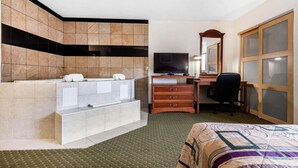 A hotel room with a large bed, a desk with a computer, a TV, and a bathroom with a bathtub and towel rack. - Quality Inn & Suites Binghamton Vestal (Binghamton)