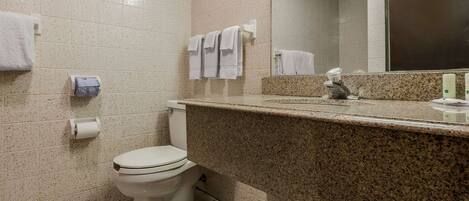 A bathroom with a toilet, a sink with a mirror, and towels on the wall.