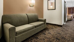 A hotel lobby with a green sofa, a wall-mounted light fixture, and a framed picture. - Quality Inn & Suites Binghamton Vestal (Binghamton)