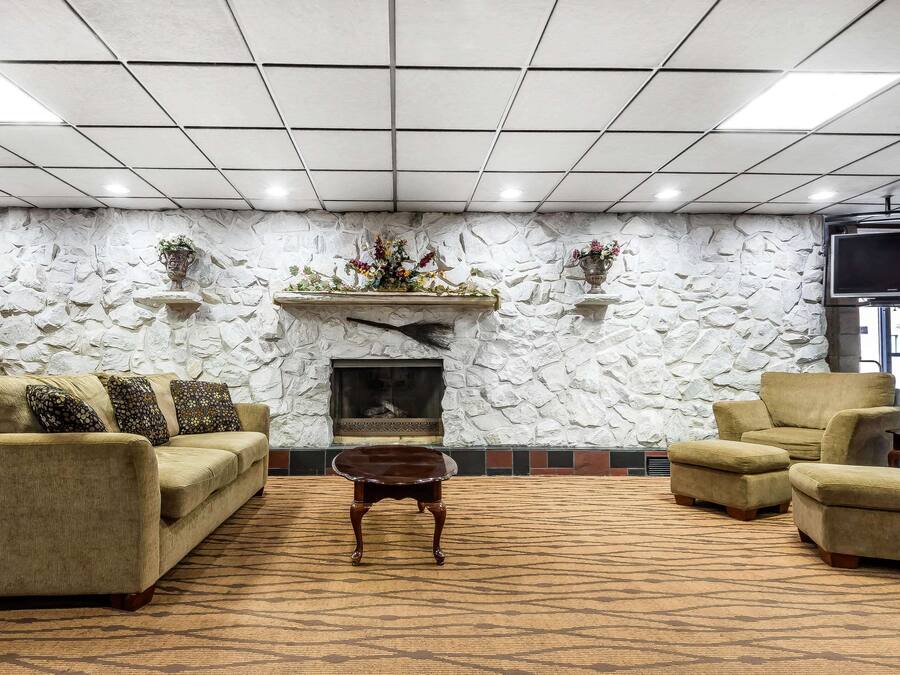 En lobby med stenvæg, pejs, sofa, sofabord og fjernsyn.