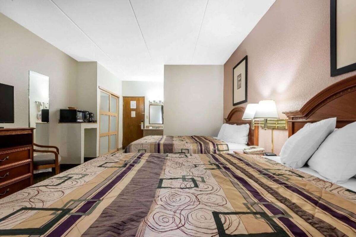 A hotel room with a large bed, a desk, a chair, a television, and a door.