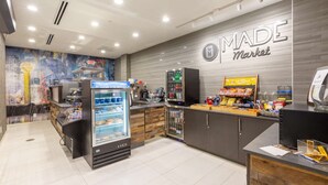 Un intérieur moderne avec une enseigne « MADE Market », un présentoir réfrigéré, une machine à café et un distributeur de boissons.