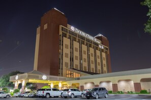 A hotel with a prominent sign, multiple floors, and a parking lot with several cars. - DoubleTree by Hilton Dallas - Richardson (Richardson)