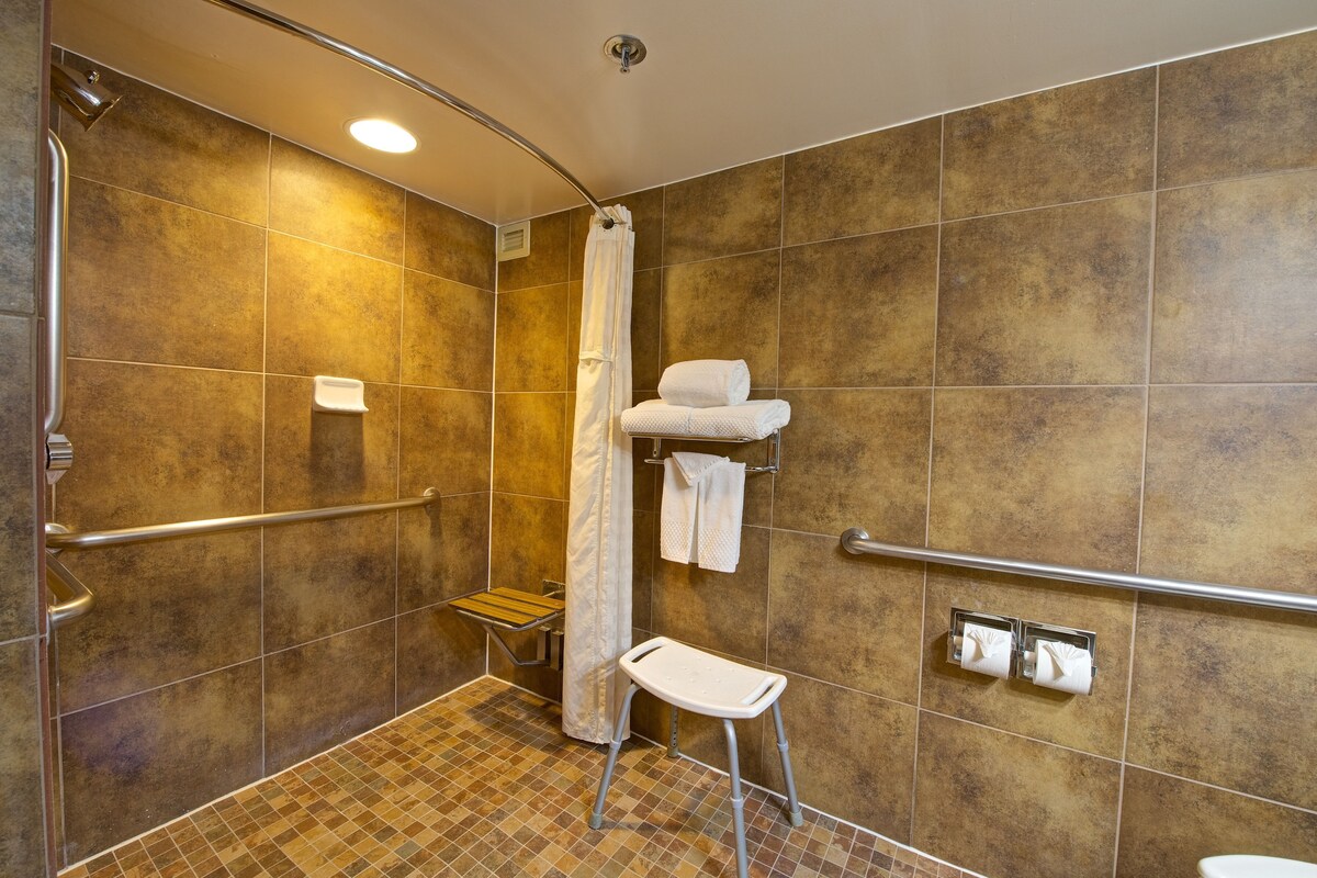 A shower area with a grab bar, a small bench, and a towel rack.
