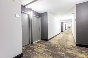 A hotel corridor with doors, a carpeted floor, and a light fixture on the ceiling. - DoubleTree by Hilton Dallas - Richardson (Richardson)