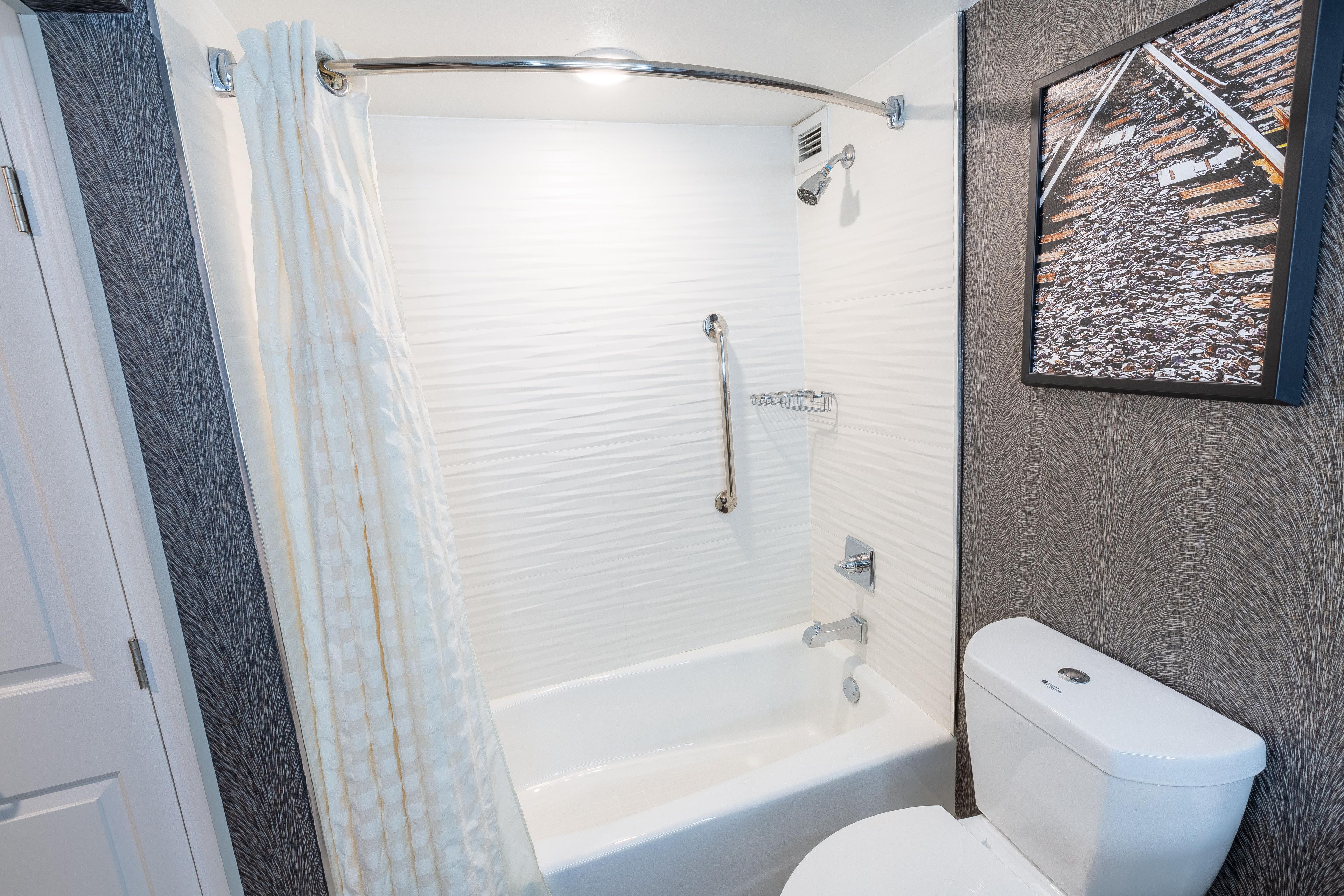 A bathroom with a bathtub, toilet, shower, and a towel rack.