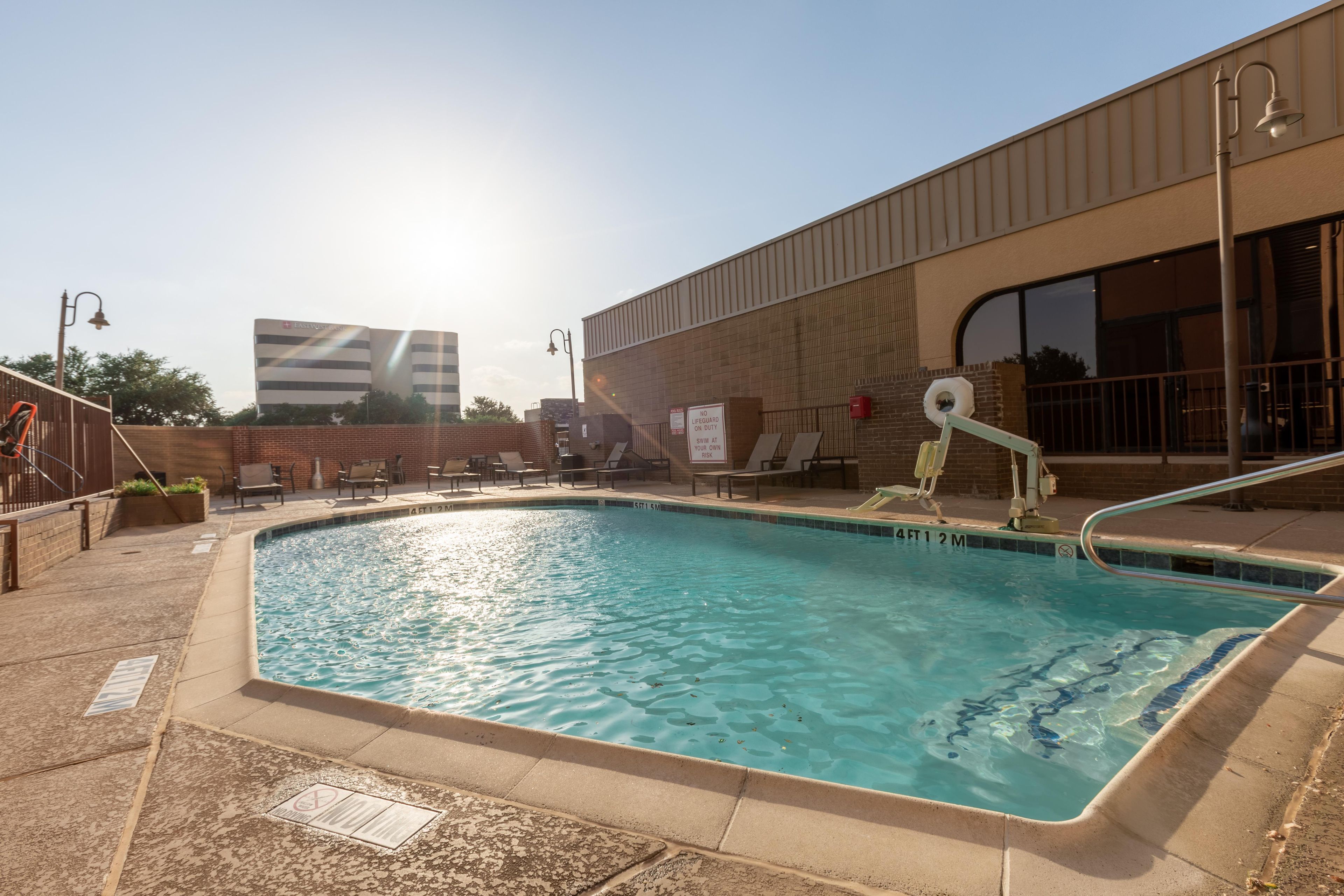 Una piscina con quiosco de salvavidas y sillas de descanso.