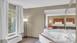 A hotel room with a large window, a standing heater, a bathtub, and a bed with a headboard. - Bristol Arcadia Inn (Bristol)