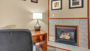 A living room with a fireplace, framed pictures on the wall, a lamp on a table, and a chair. - Bristol Arcadia Inn (Bristol)