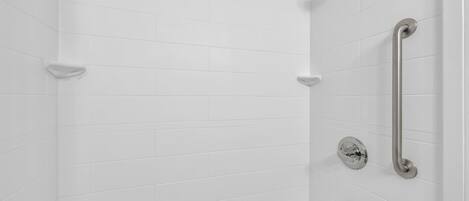 Eine Dusche mit weiß gefliesten Wänden und drei Handbrausen.