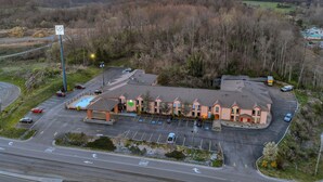 An aerial view of a hotel with a parking lot, a swimming pool, and a building with a unique architectural style. - Bristol Arcadia Inn (Bristol)