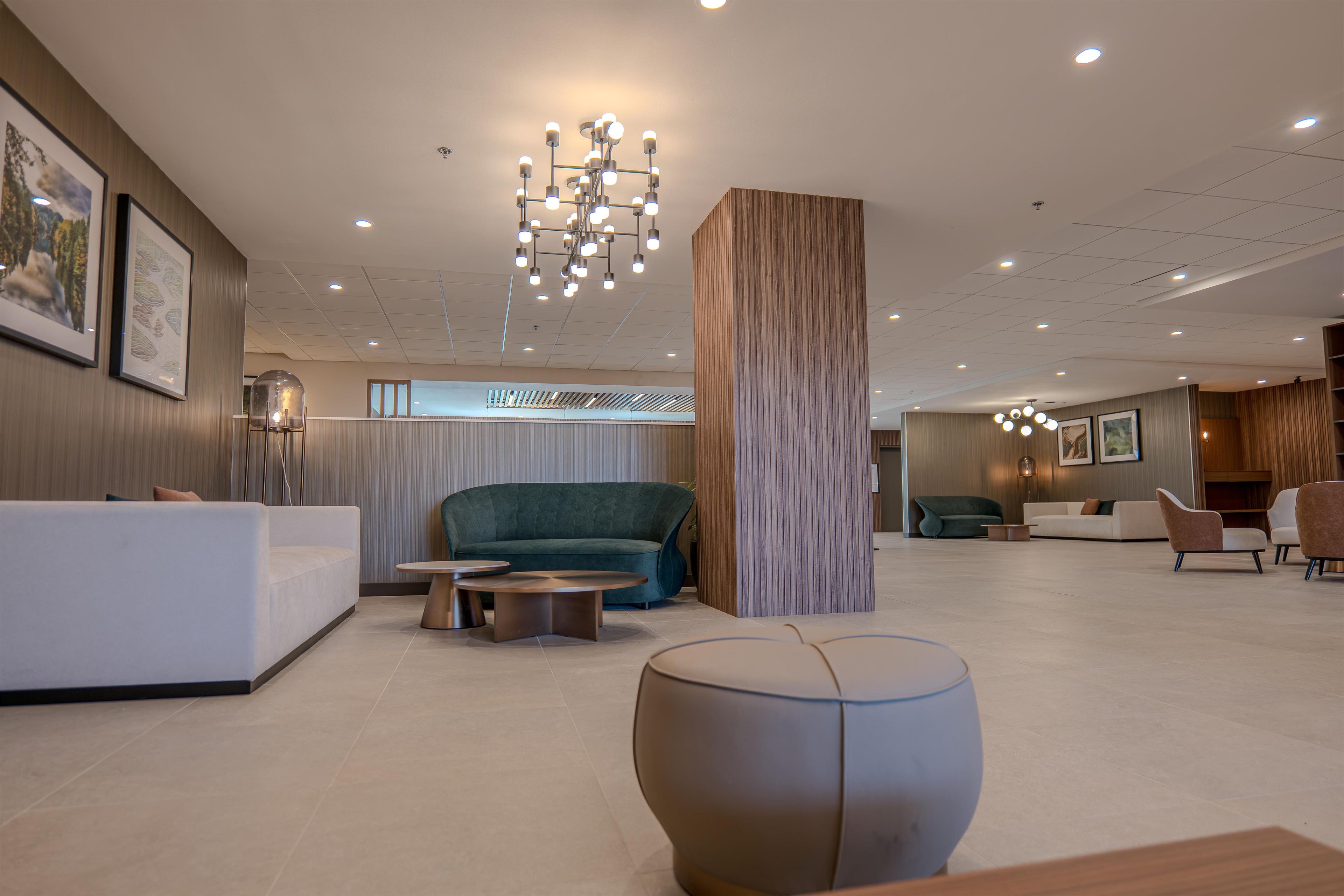 A modern lobby with a reception desk, seating area, and a large column.