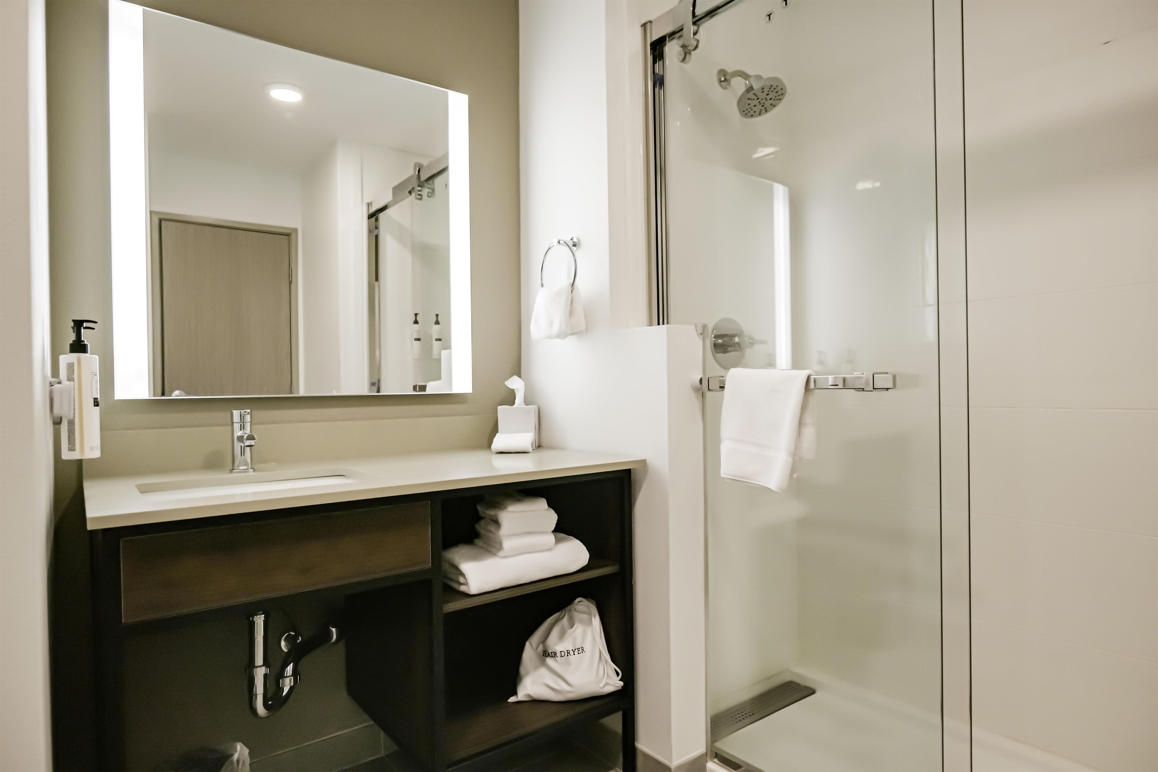 A modern bathroom with a glass shower enclosure, a vanity with a mirror, and a towel rack.