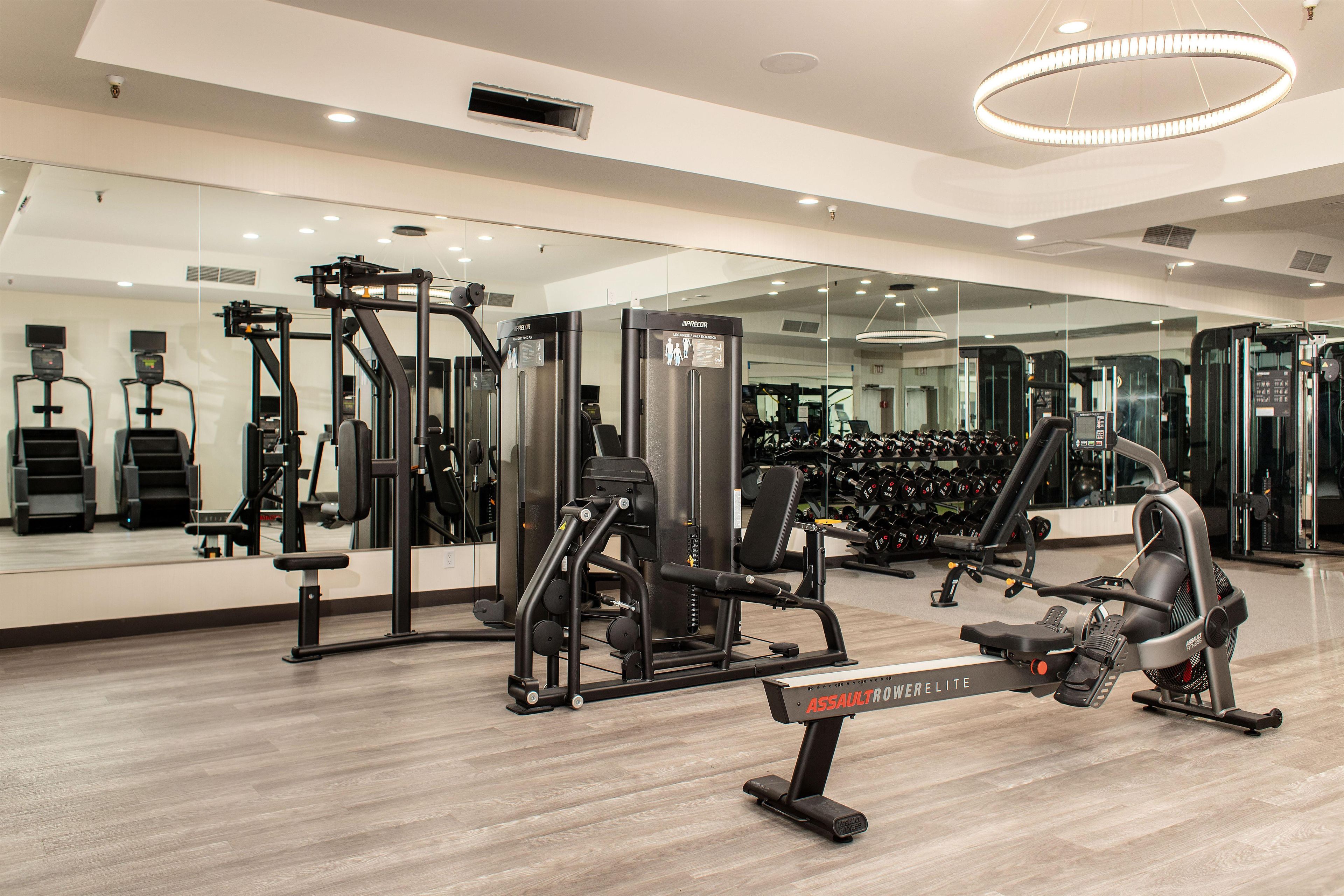 Un gimnasio con diversos equipos de ejercicio, incluyendo una máquina de remo y máquinas de pesas.
