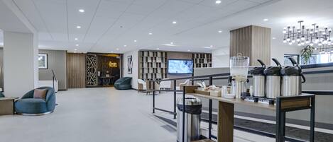 A modern lobby with seating, a coffee station, and a television.
