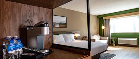 Une chambre d’hôtel avec un bureau en bois, un minibar et un lit donnant sur le paysage urbain.