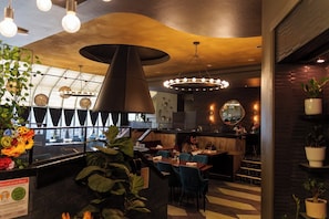 A modern restaurant interior with a bar area, seating arrangements, and a large decorative light fixture.