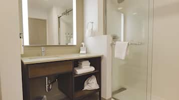 A modern bathroom with a glass shower enclosure, a sink with a mirror, and a towel rack.