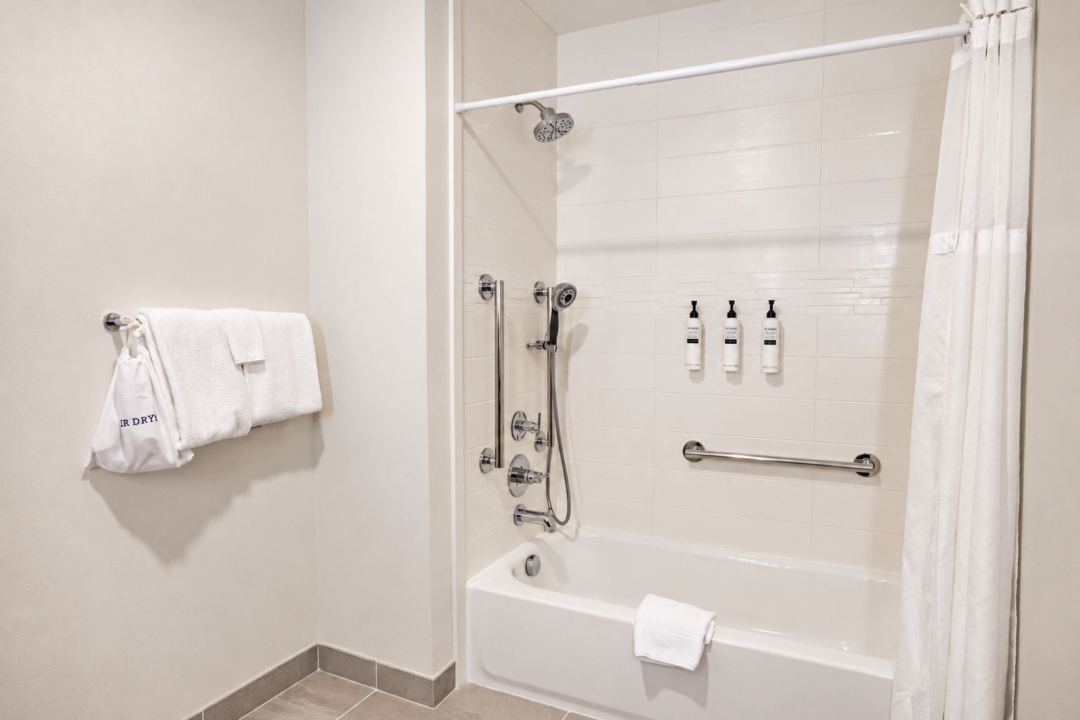A modern bathroom with a glass-enclosed shower, a bathtub, and a towel rack with towels.