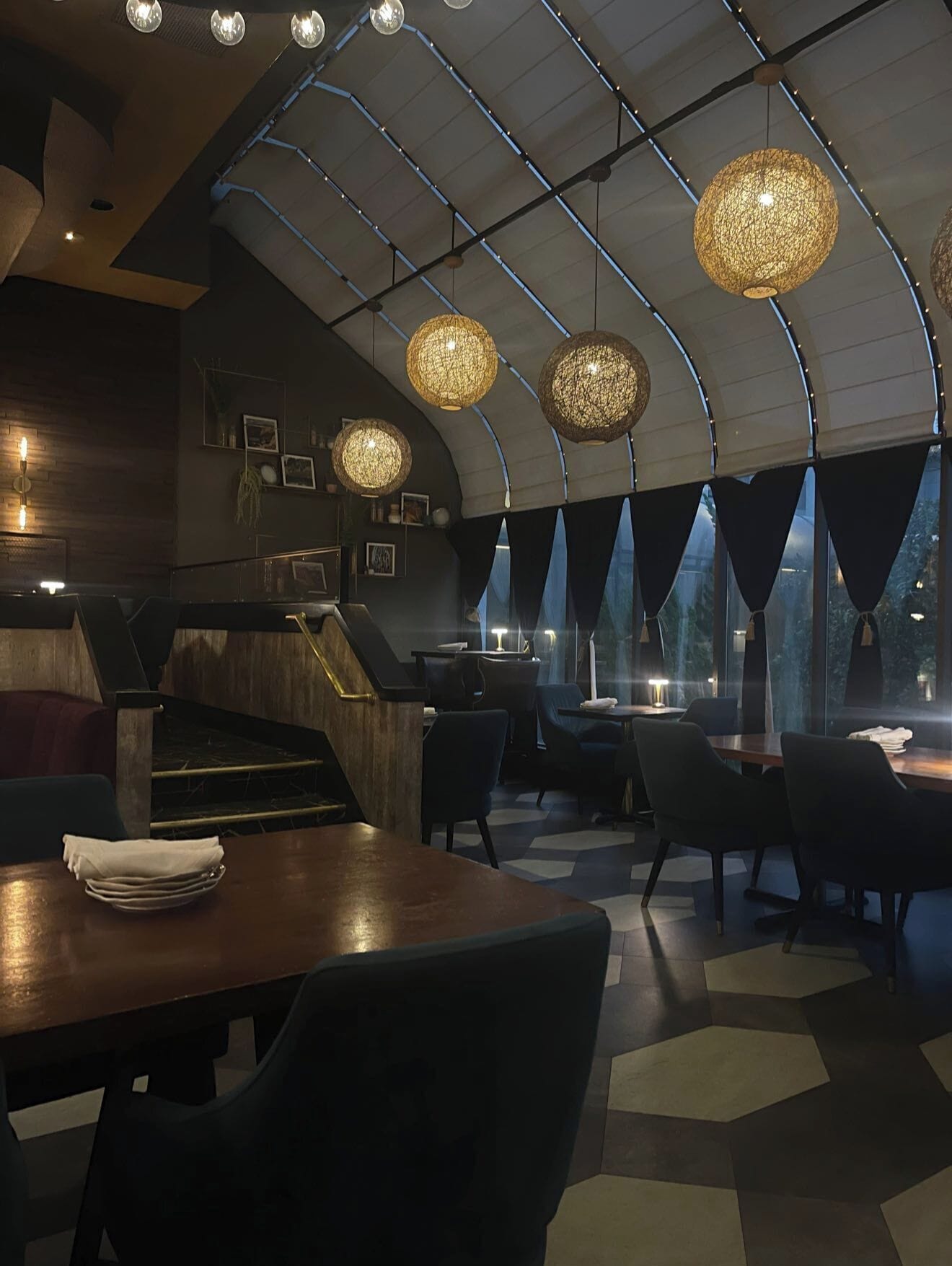 En restaurant med buet loft, hængende sfæriske lysekroner og moderne indretning.