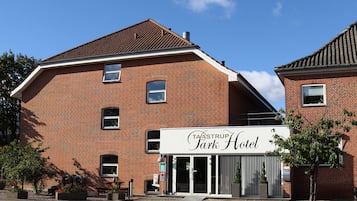 Classic hotel entrance with a glass door and landscaped surroundings.
