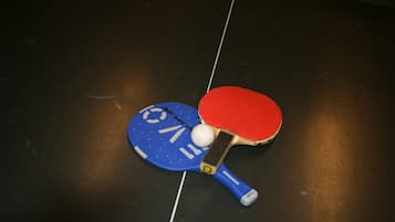 A table tennis table with a blue paddle and a red paddle, a ball, and a net.