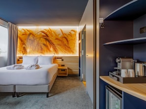 A hotel room with a bed, a nightstand, a coffee machine, and a minibar. - Mercure Lyon Est Villefontaine (Vaulx-Milieu)