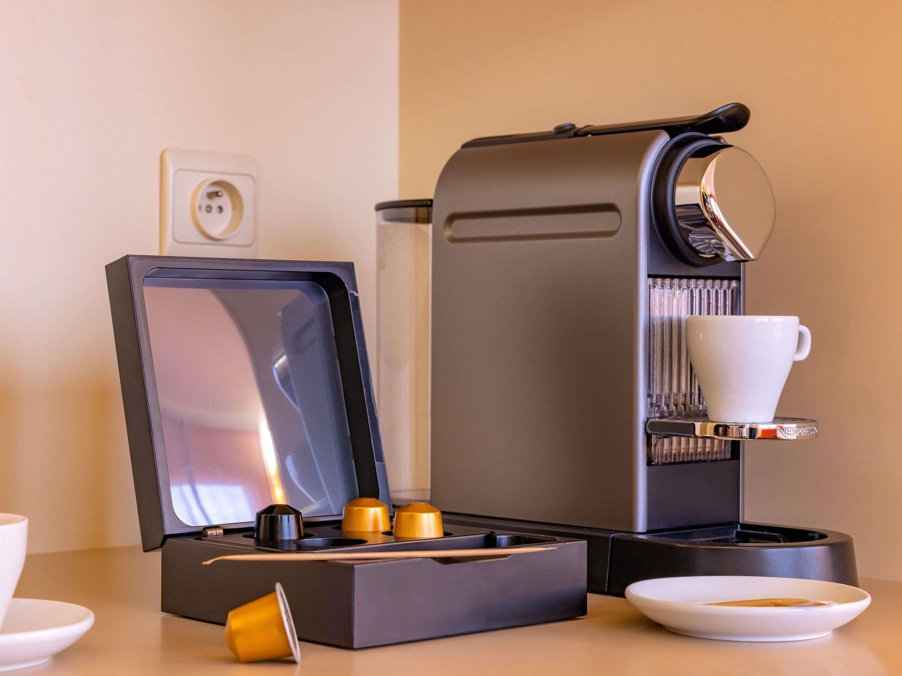 Una macchina da caffè con un portabicchieri, un portacapsule e un piatto su un tavolo.