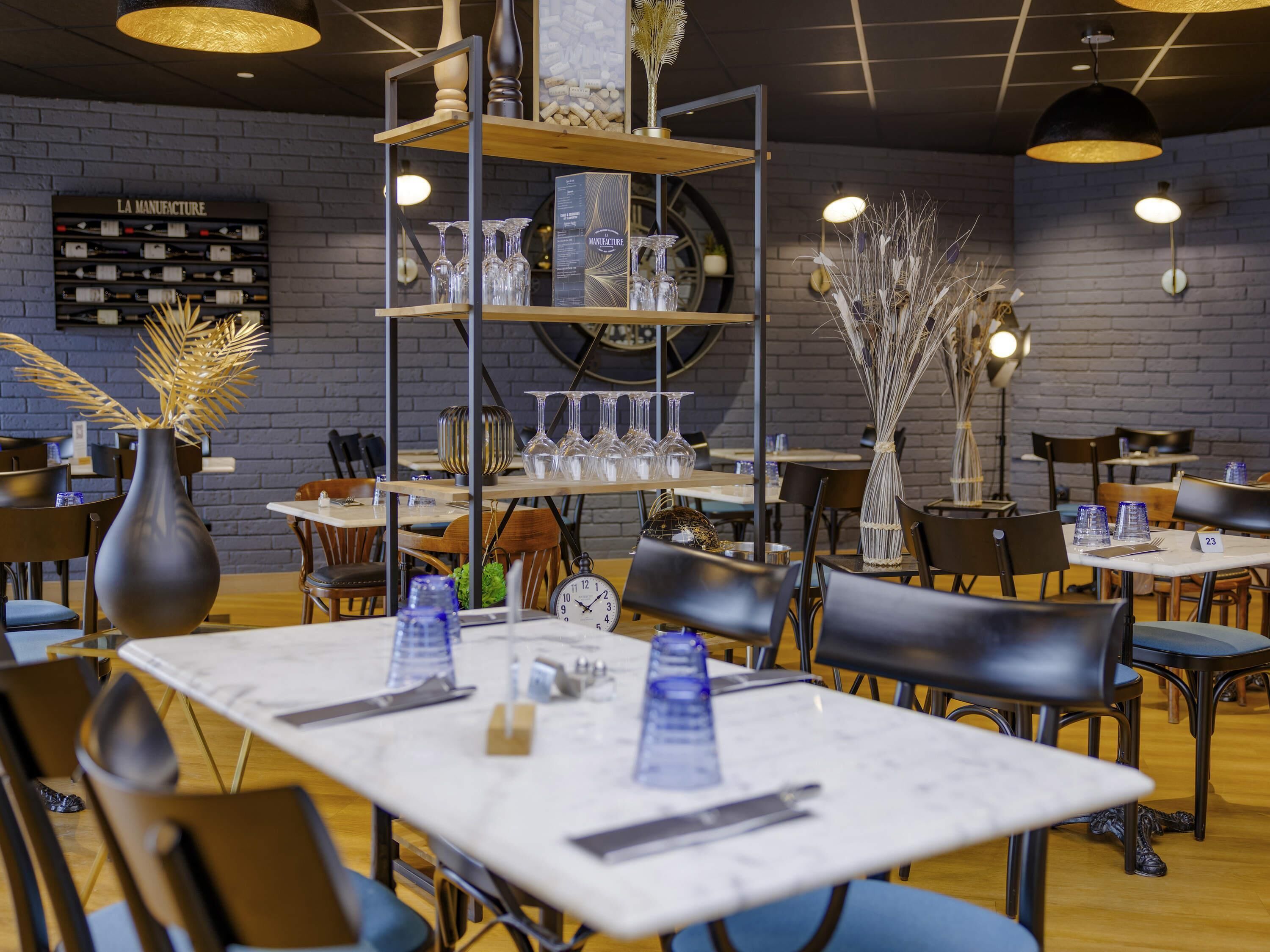 Een restaurantinterieur met tafels, stoelen, een klok en een plank met glazen.
