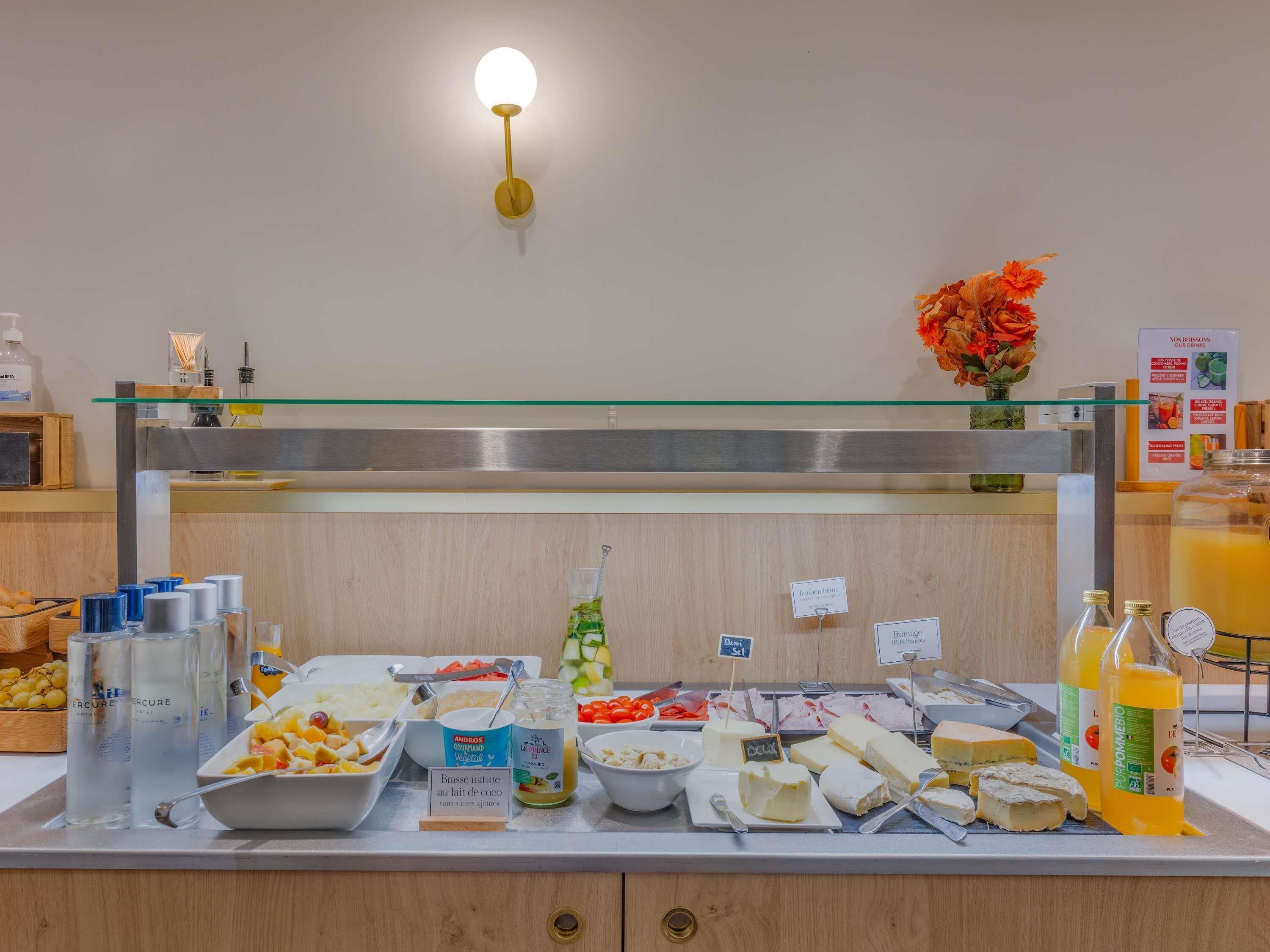 A buffet with various cheeses, fruits, and beverages.