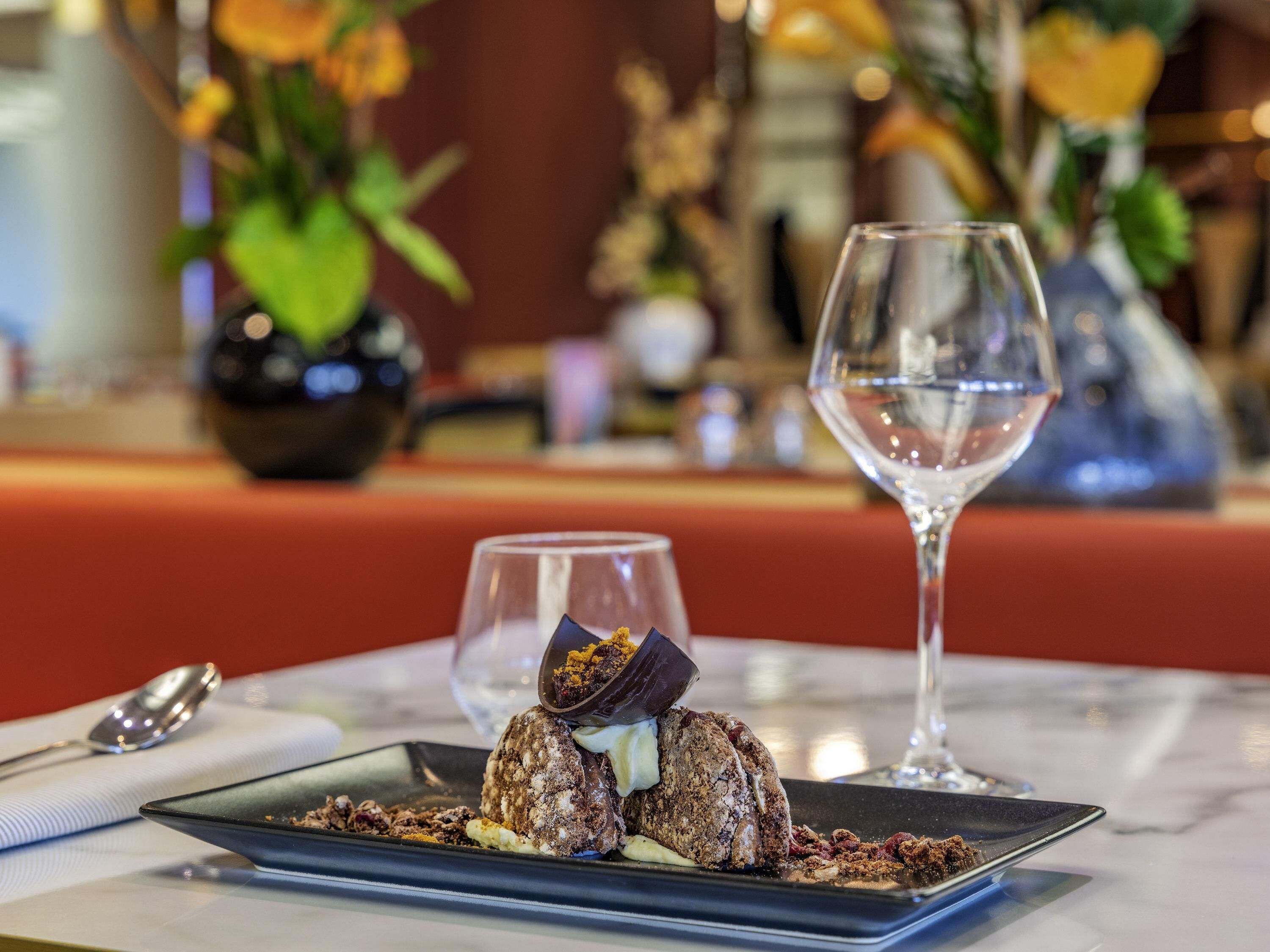 A dessert plate with a chocolate dessert and a glass of water on a table.