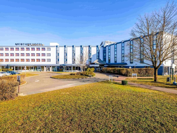 A modern hotel with a clear entrance, a parking area, and a well-maintained lawn. - Mercure Lyon Est Villefontaine (Vaulx-Milieu)