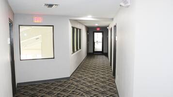 A hallway with patterned carpet, exit signs, and doors leading to other areas.
