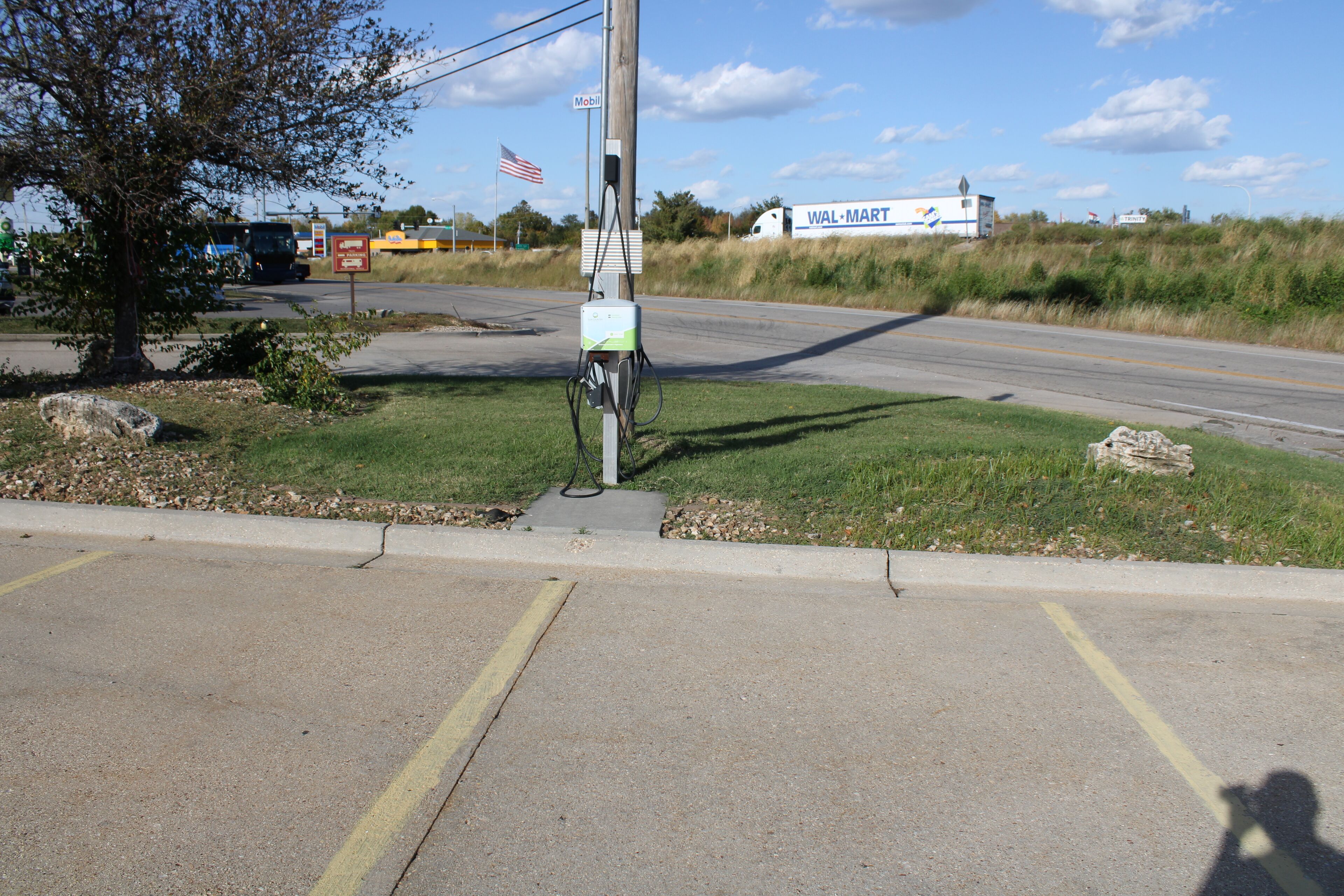 Eine Ladestation für Elektroautos am Straßenrand, im Hintergrund ist ein Walmart-Markt sichtbar.