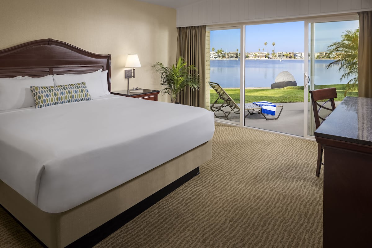 Une chambre d’hôtel avec un grand lit, un bureau, une chaise, une lampe et une vue sur une étendue d’eau.