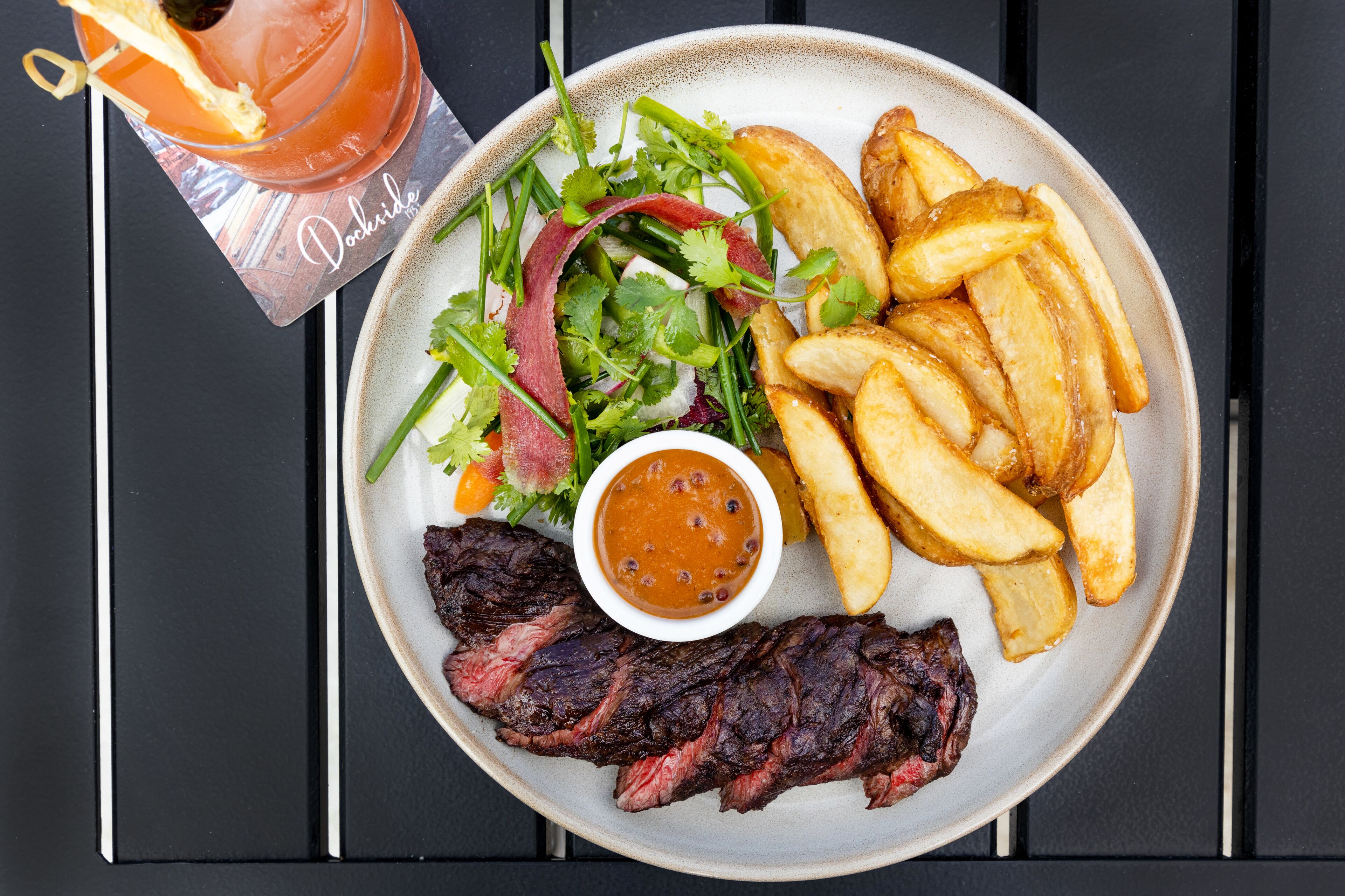 Ein Teller mit Steak, Pommes, Salat und Soße.