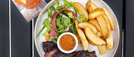 Ein Teller mit Steak, Pommes, Salat und Soße.