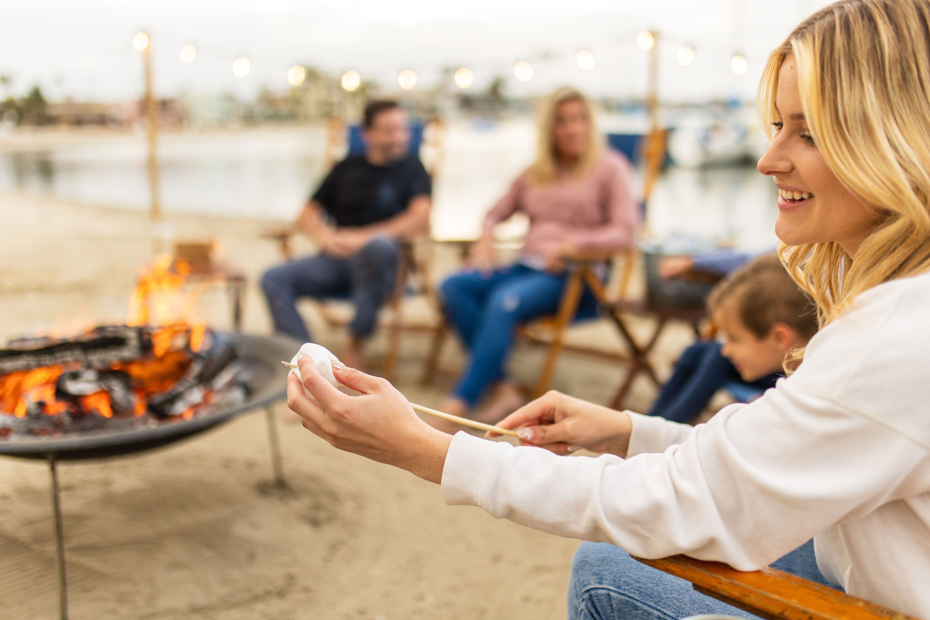 A person grilling outdoors with a fire visible in the foreground.