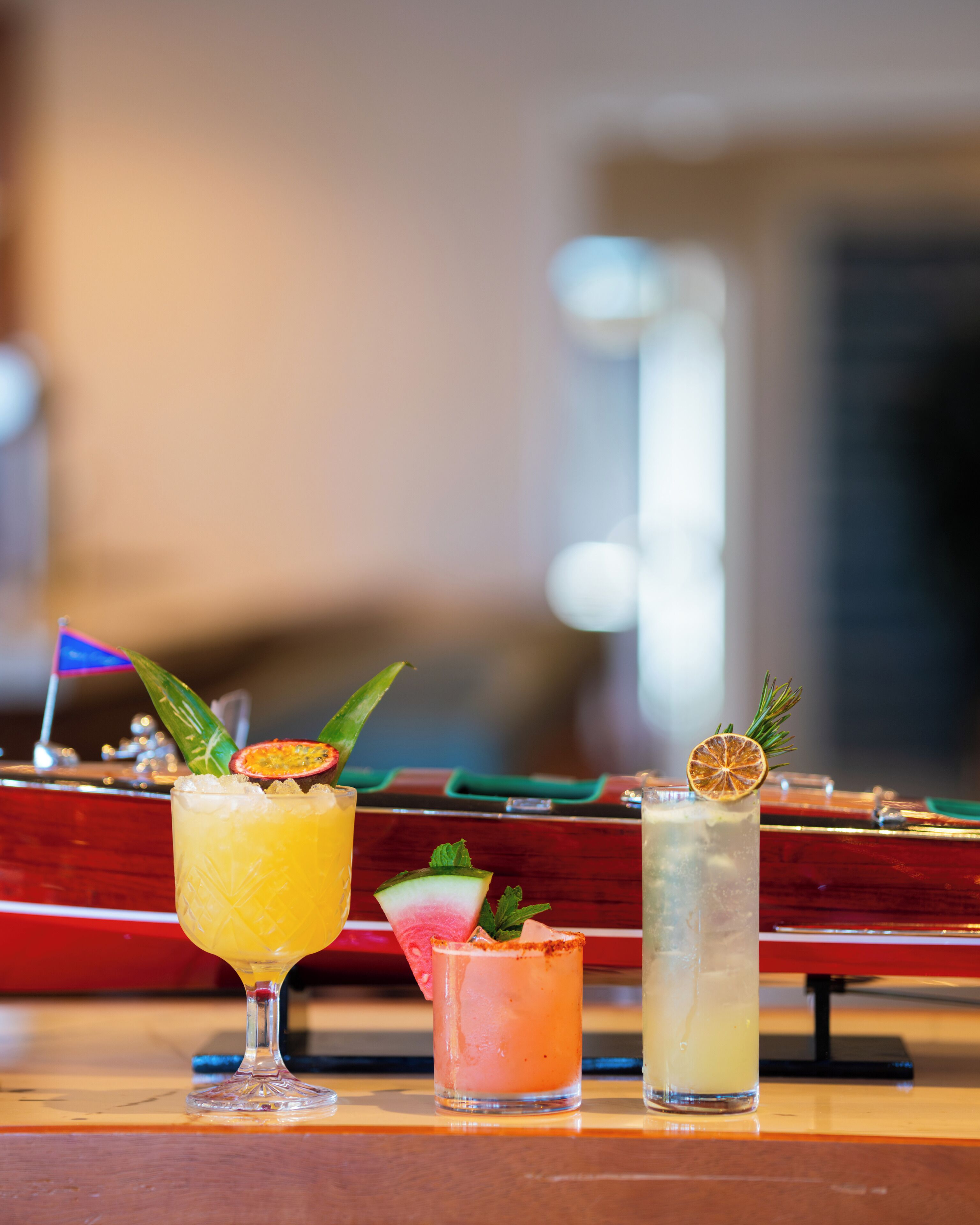 Three cocktails on a bar counter with a blurred background.